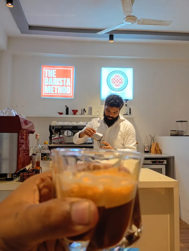 The instructor working at the lab bar, with a glass of espresso held up in the foreground
